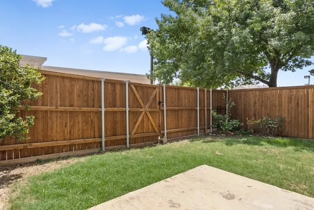 Private backyard featuring a full wood fence with gate, concrete patio, and mature landscaping