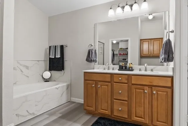 Dual vanity with wood cabinetry, large vanity mirror, white countertop, and contemporary light fixture