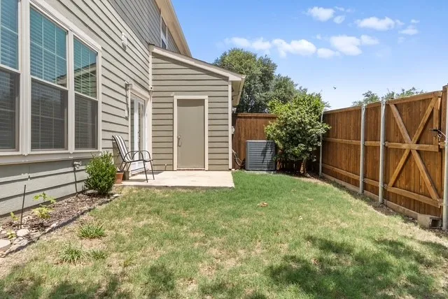 Backyard space featuring a wooden fence, a small paved patio, and a side door entry