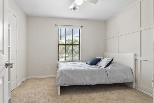 Carpeted flooring, window with blinds, ceiling fan with integrated lighting, and board-and-batten wall detailing