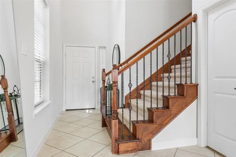 Wood staircase with decorative wrought iron spindles and carpeted treads