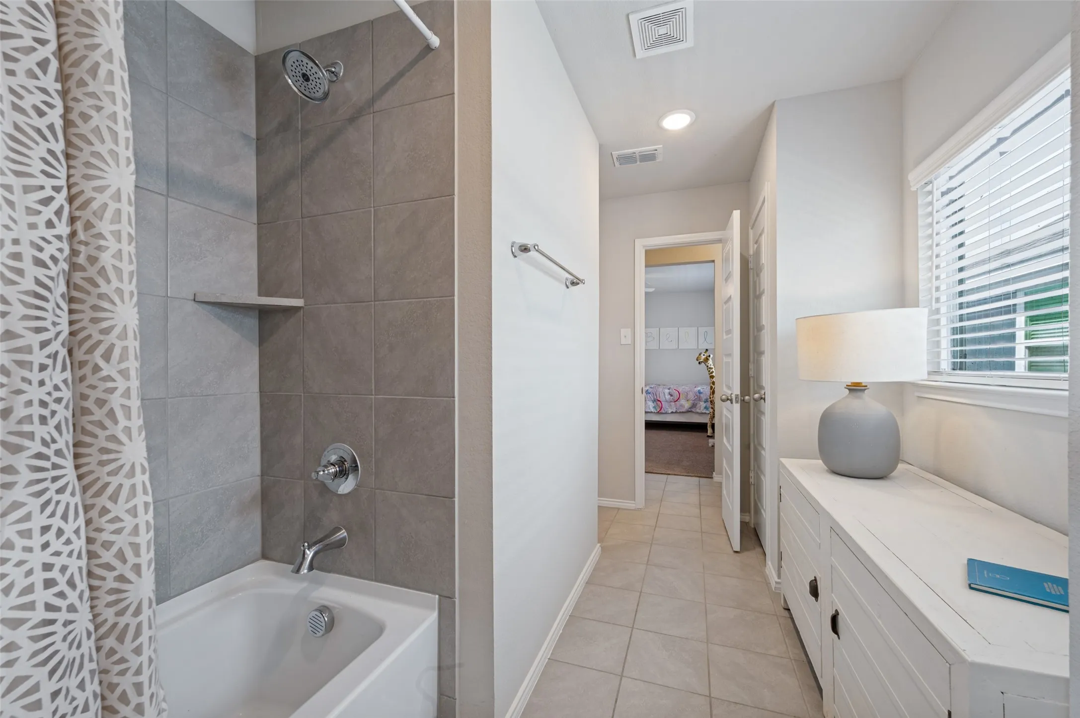 Bathtub with tiled shower surround, integrated shelf, and chrome fixtures