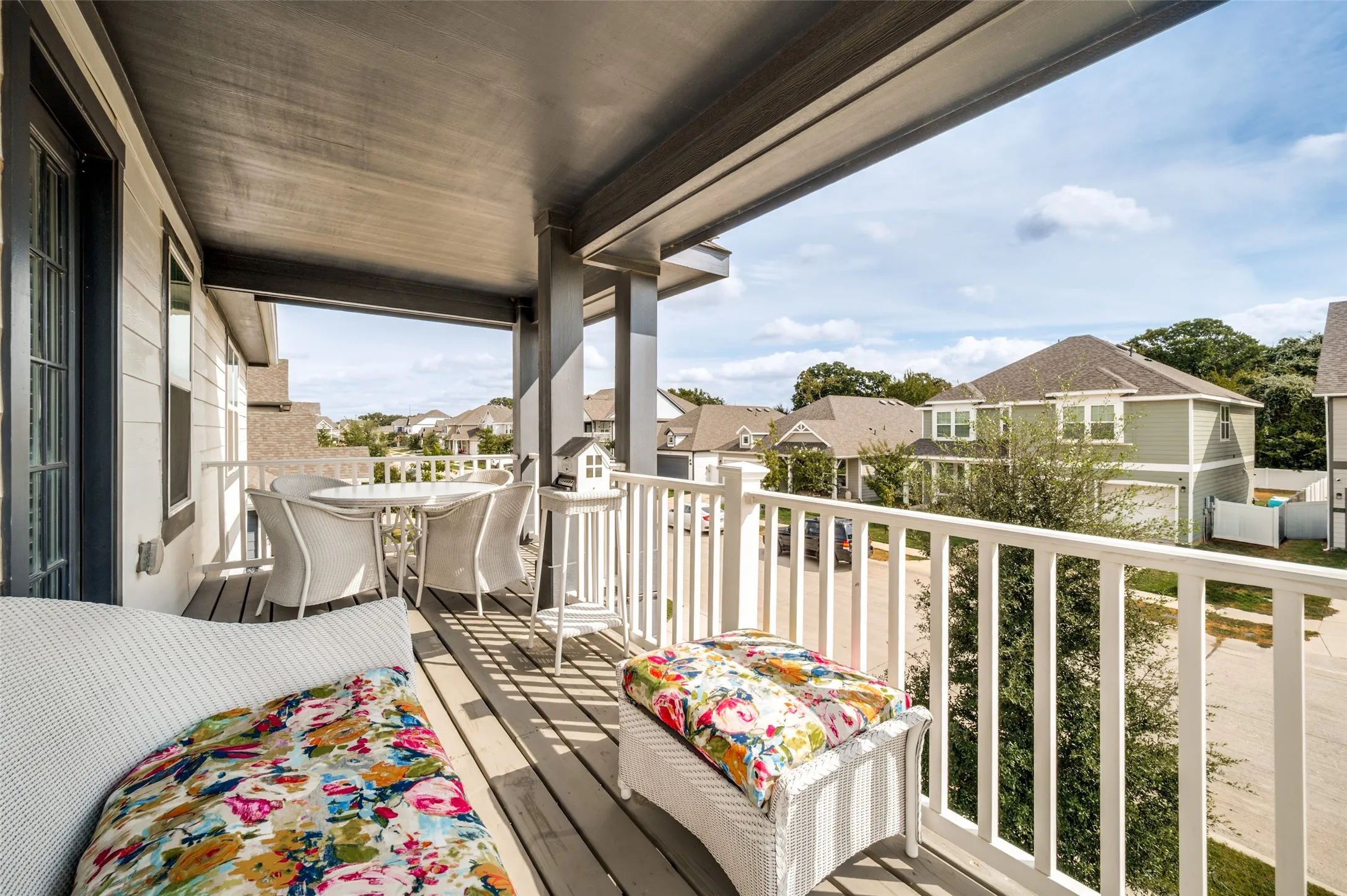Covered balcony with wood-finish flooring and white railings