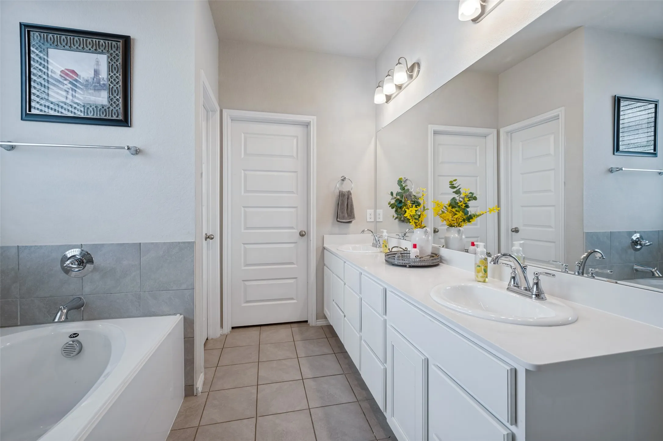 Dual vanity with undermount sinks, white cabinetry, and an expansive mirror