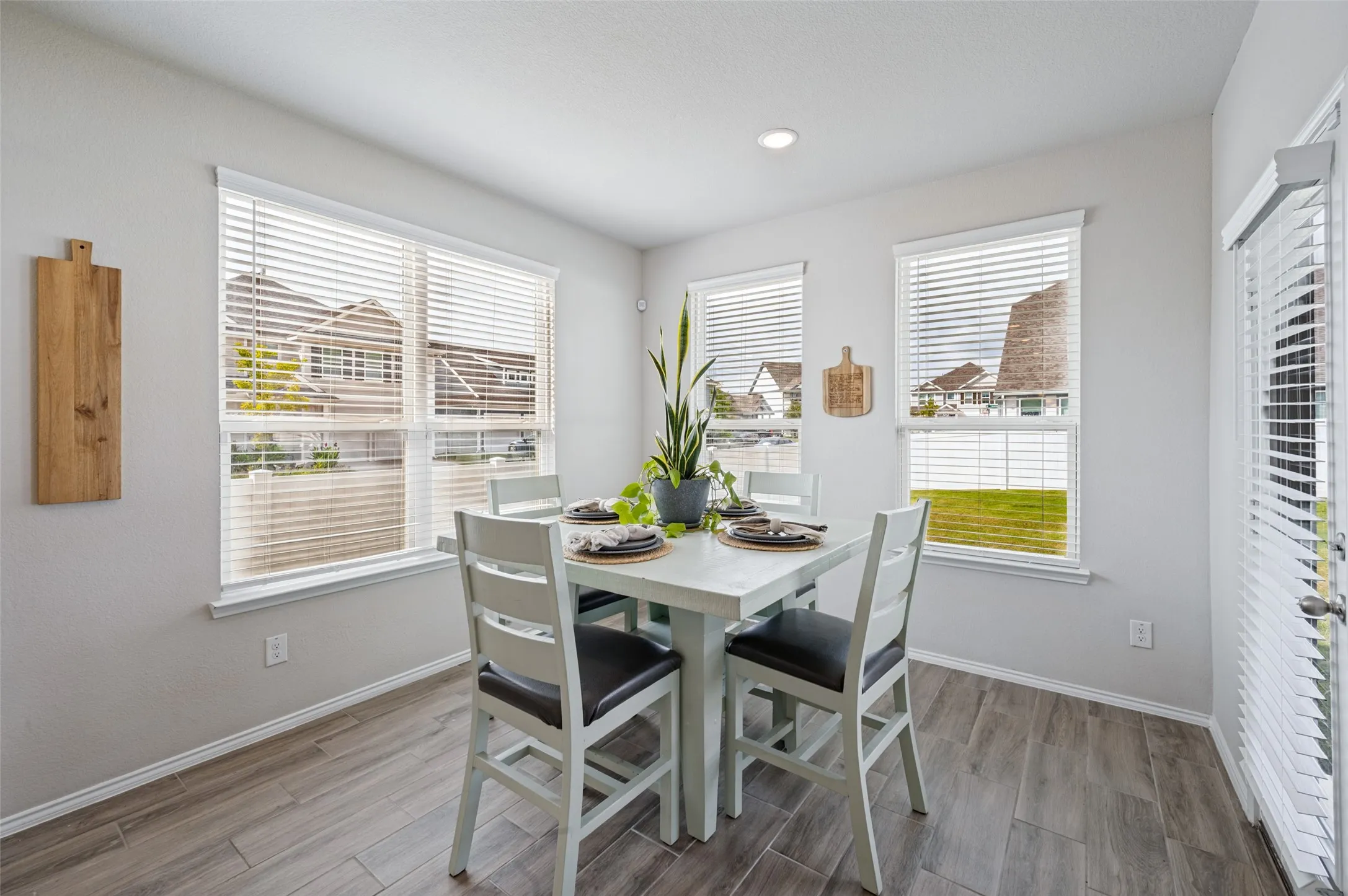 Recessed lighting, multiple windows with blinds, wood-finish flooring, and a white paneled door