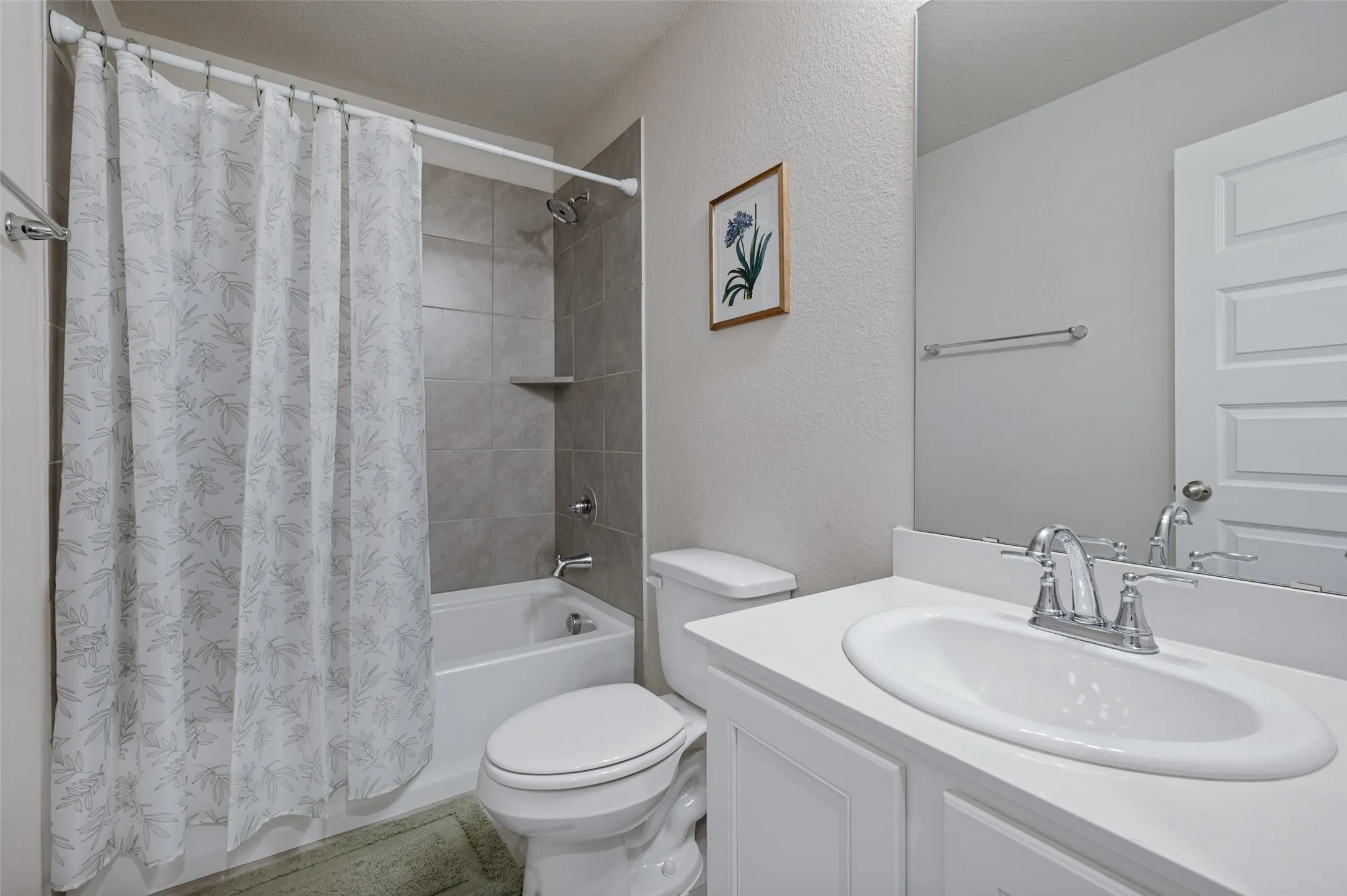 Bathroom featuring a bathtub with tiled surround, a built-in shower niche, a white vanity with an integrated sink, and chrome fixtures