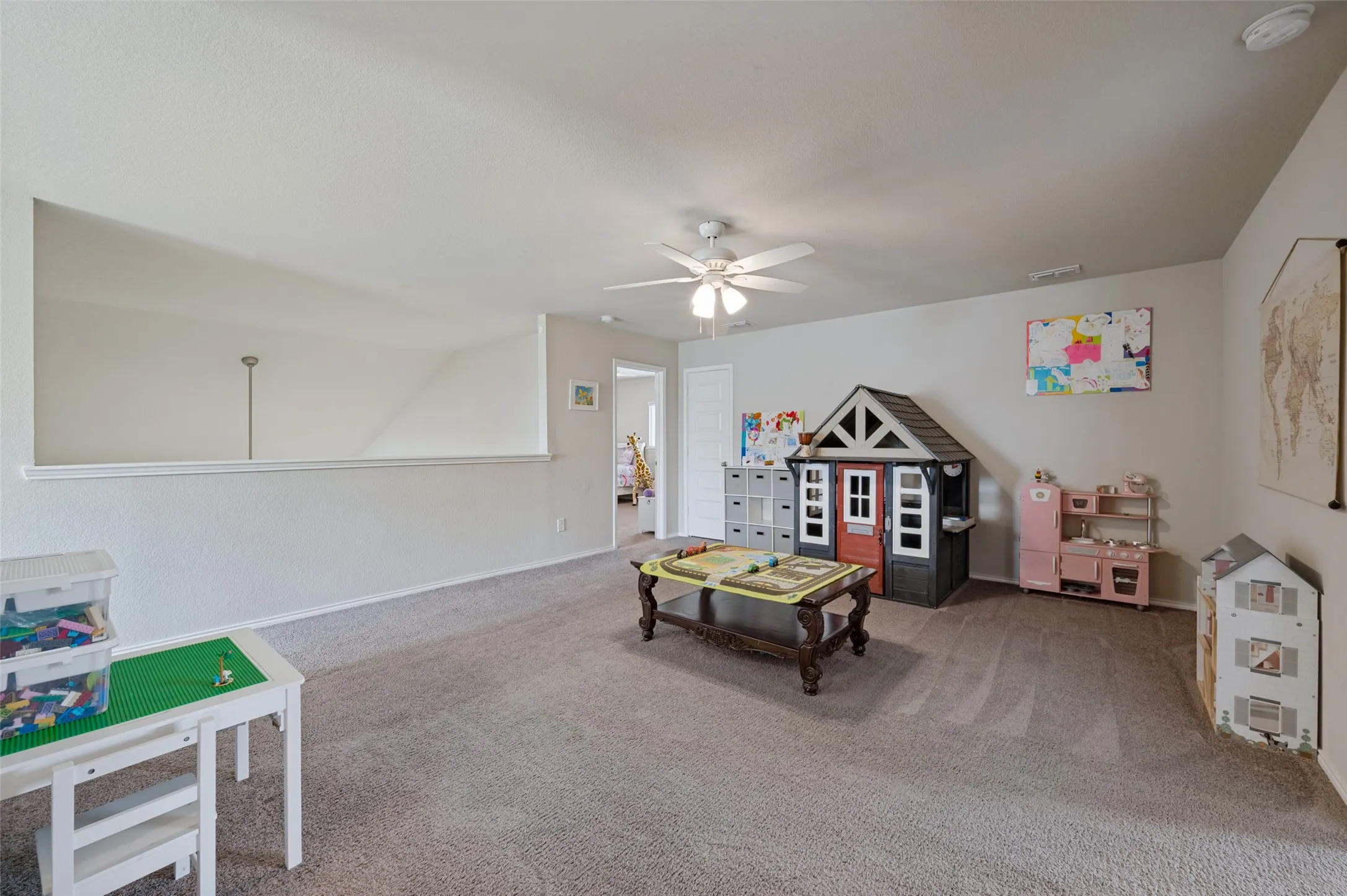 Expansive room with carpet flooring, light-toned walls, and a ceiling fan with integrated lighting