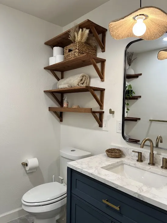Bathroom featuring a dark blue vanity, white countertop, brass-finish faucet, and a wall-mounted mirror