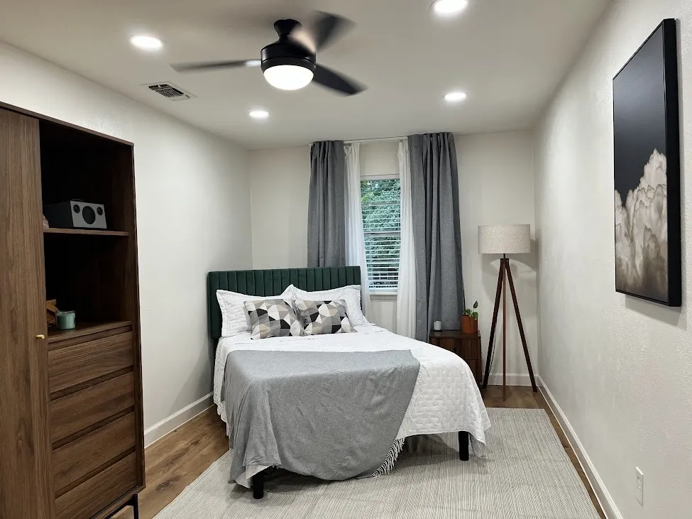 Recessed ceiling lighting, wood-finish flooring, built-in shelving, window with blinds and drapes, and a ceiling fan with integrated lighting