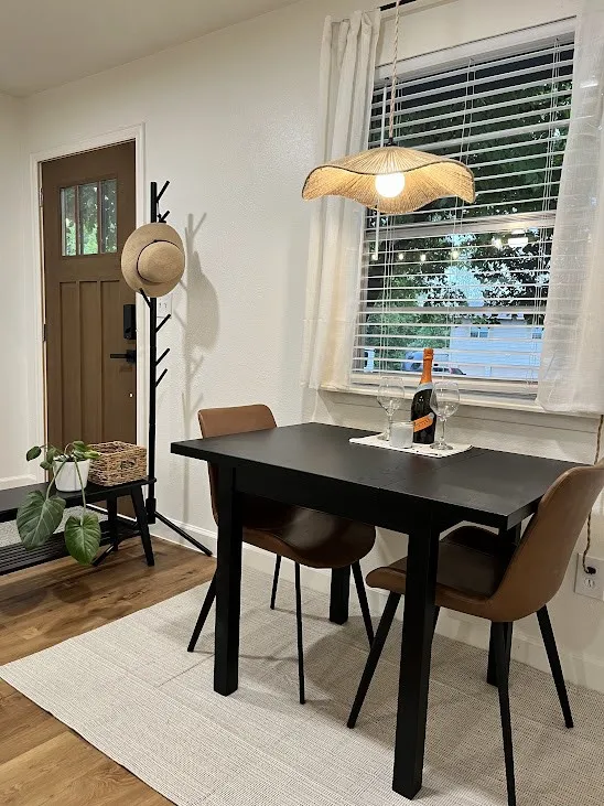 Wood-finish flooring, white painted walls, and a window with blinds and white curtains