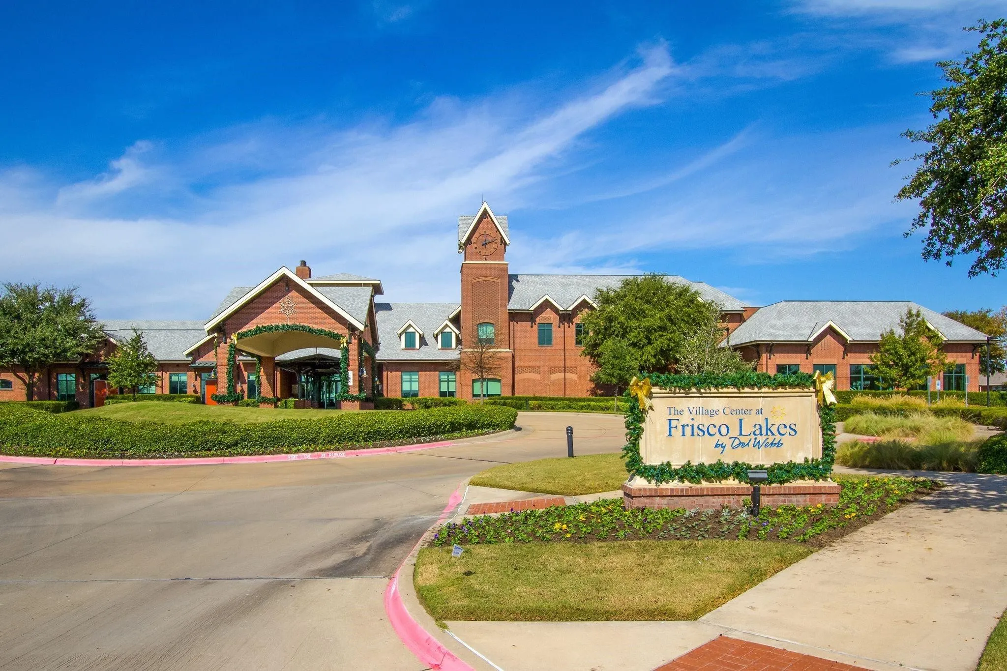 Red brick exterior, prominent clock tower, gabled entry, grey shingle roofing, and established landscaping