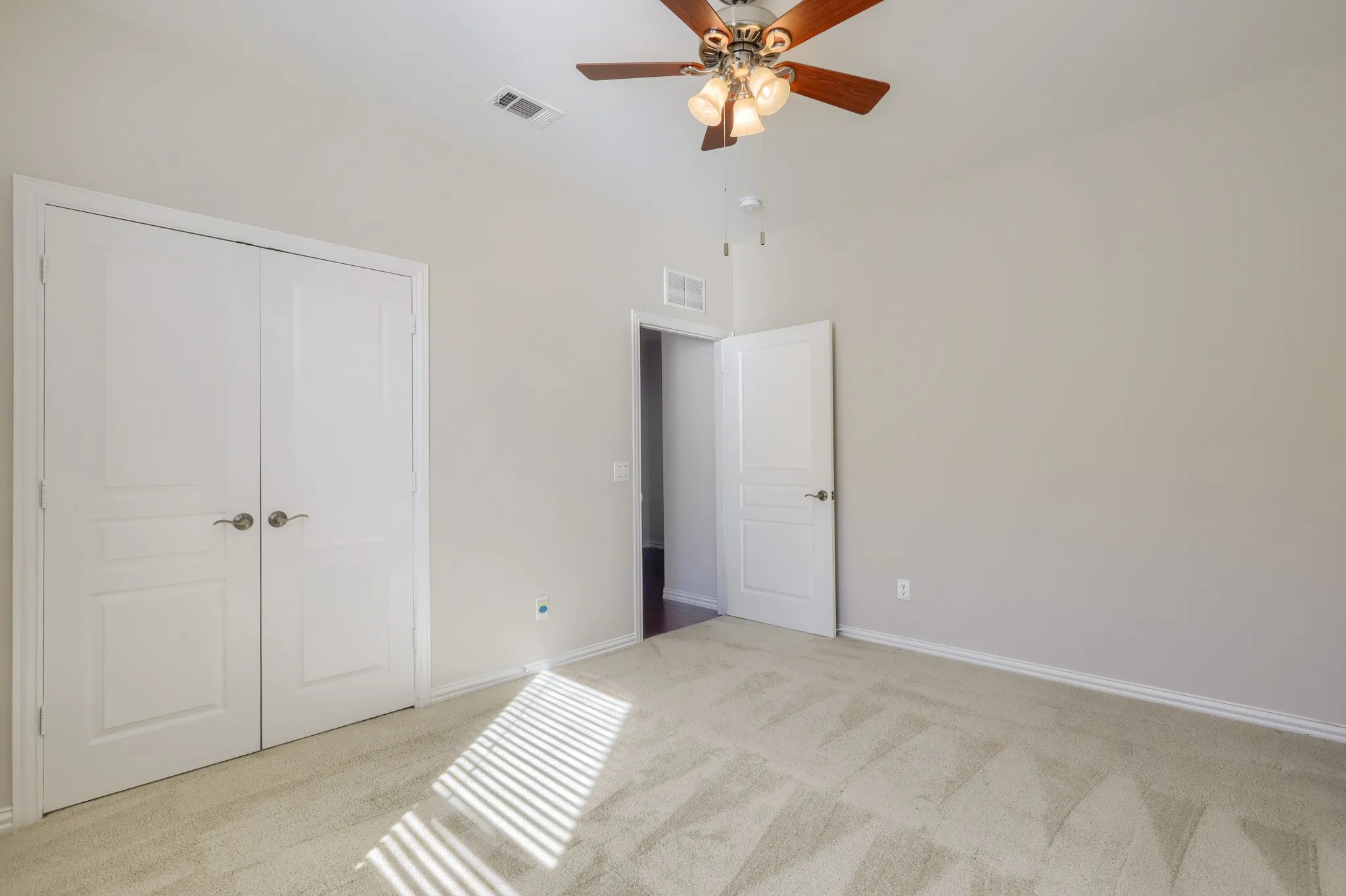 Plush carpet flooring, light neutral wall tones, and a ceiling fan with integrated lighting