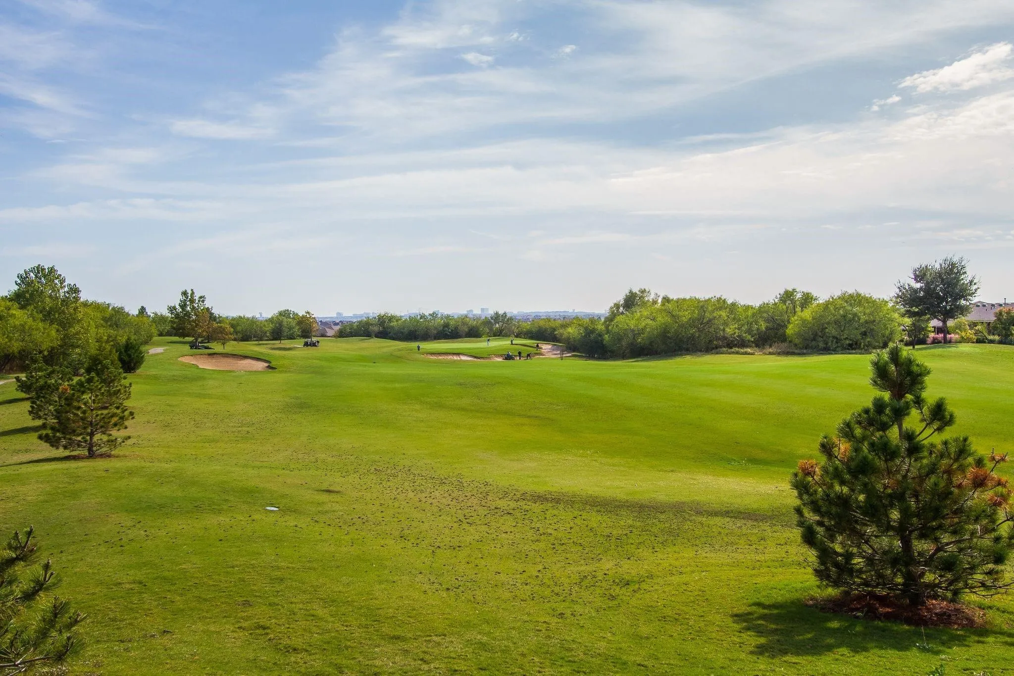 Expansive golf course setting featuring manicured greens, sand traps, and mature trees