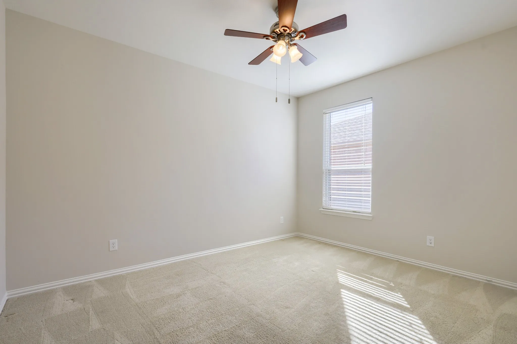 Neutral-toned walls, light-toned carpet flooring, window with horizontal blinds, and a ceiling fan with integrated lighting
