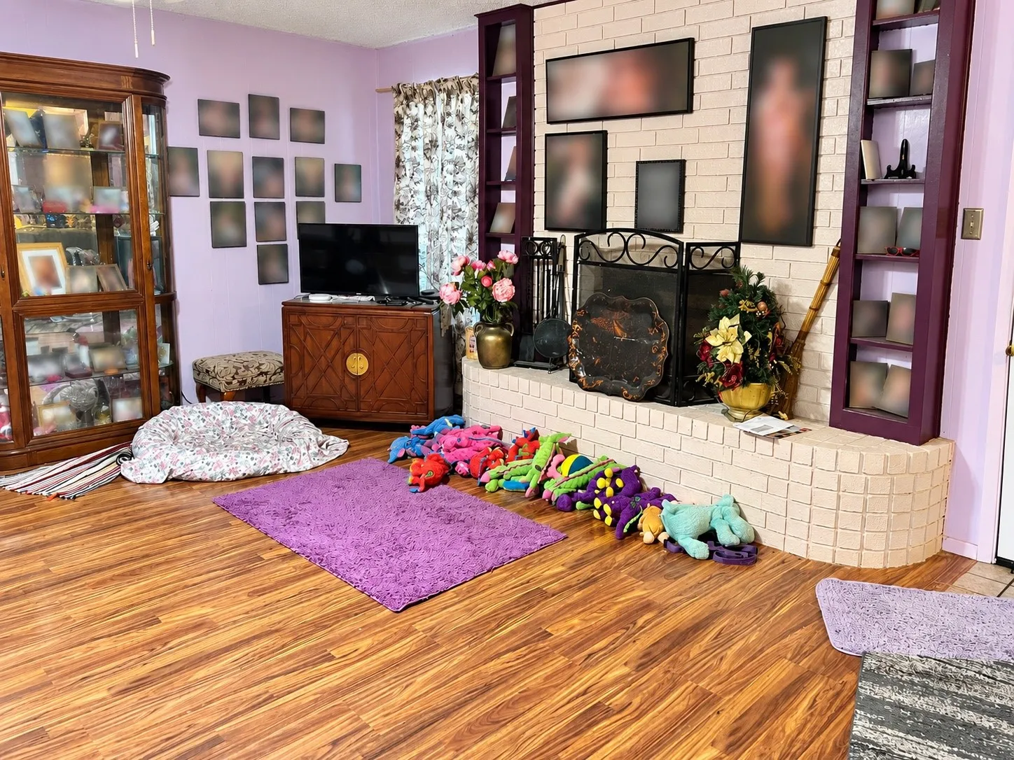 Wood-finish flooring with a brick fireplace, built-in shelving, and a prominent display cabinet