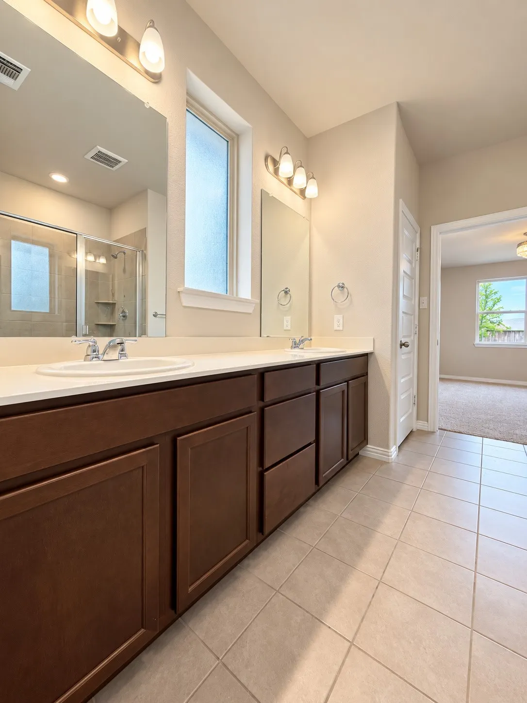 Dual vanity with undermount sinks, warm wood-finish cabinetry, and light-toned countertops