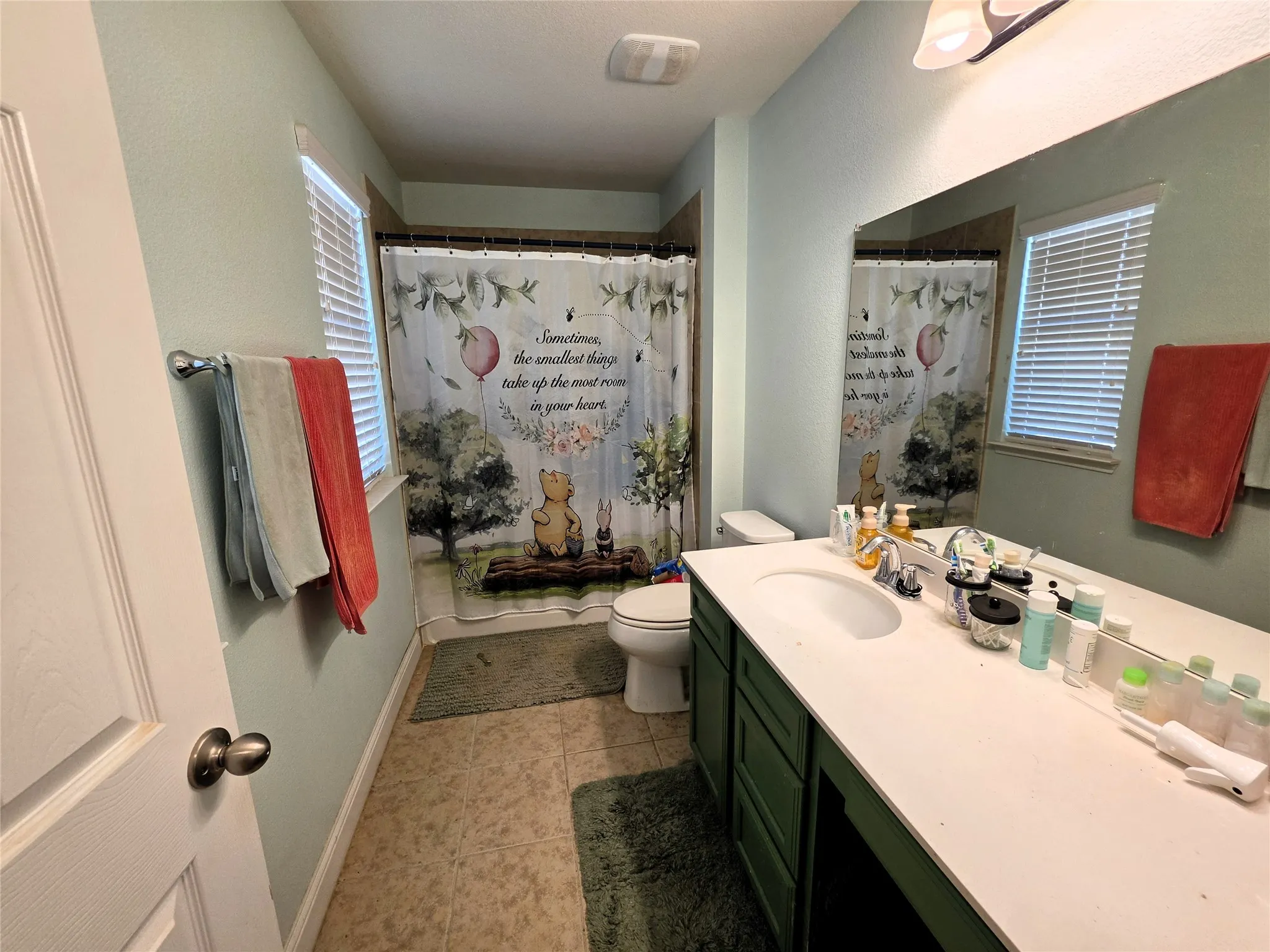 Bathroom featuring a single vanity with an integrated sink, white countertop, and a large mirror