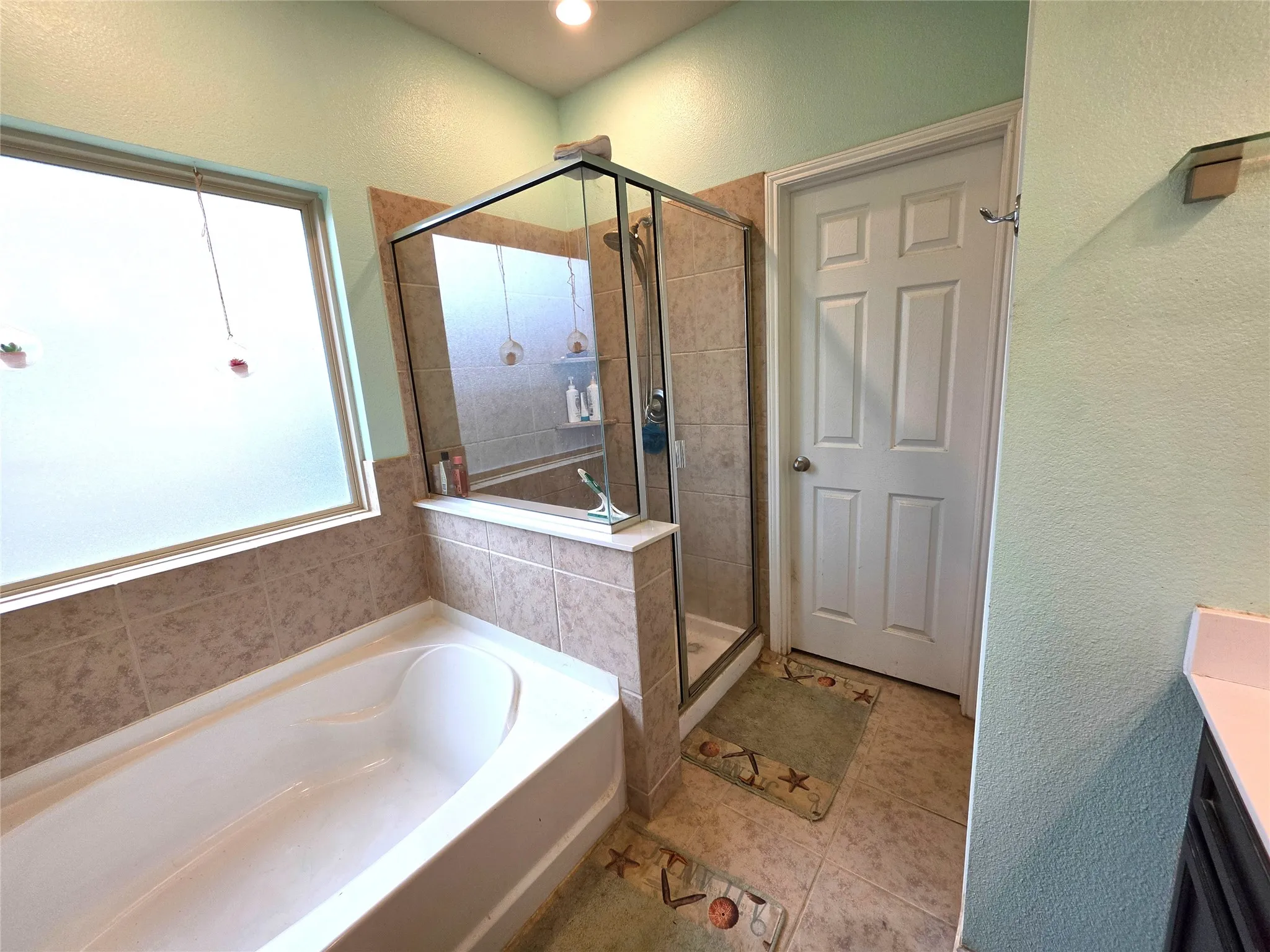 Built-in bathtub with tiled surround, glass-enclosed shower, and tiled flooring
