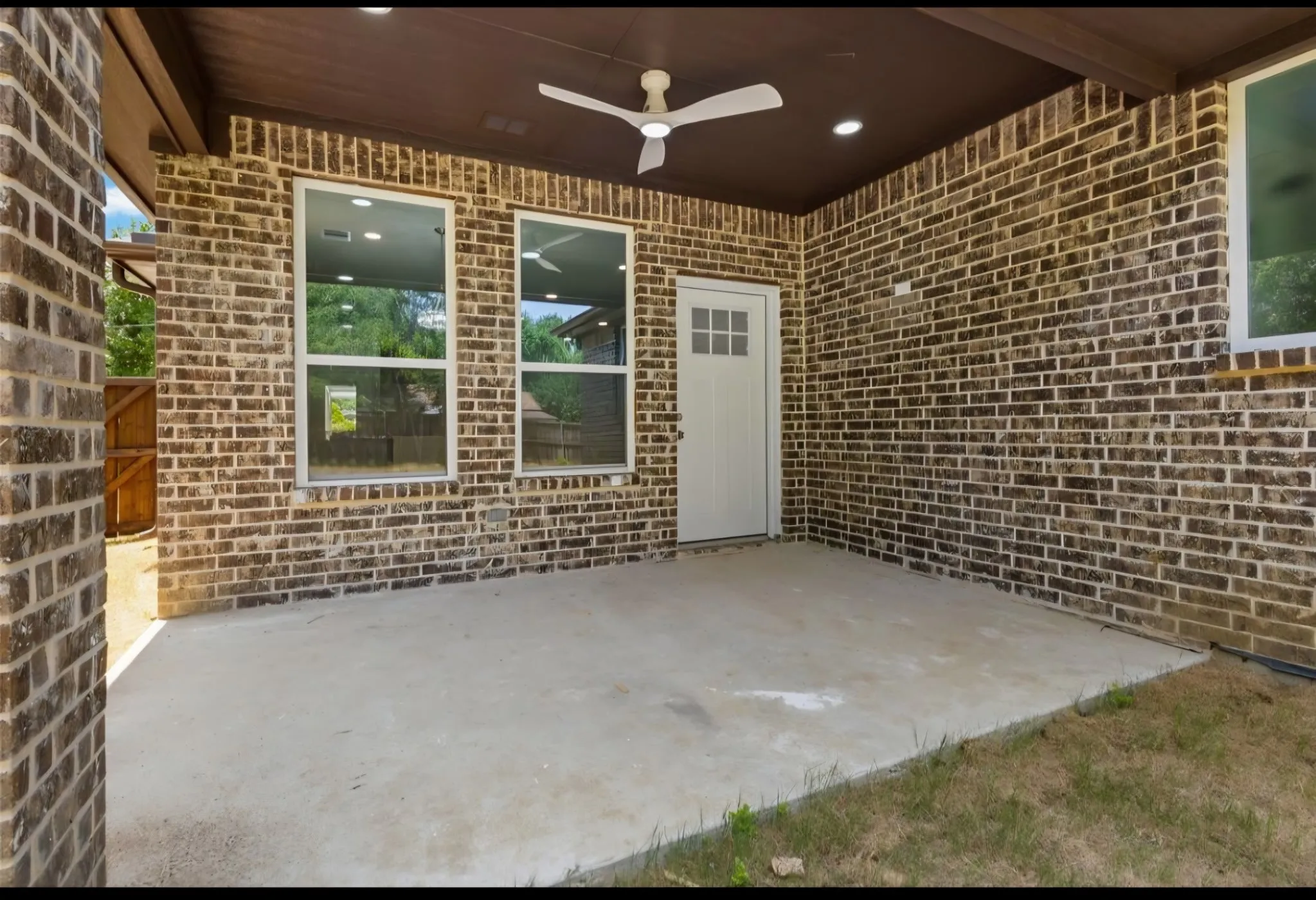 Covered patio featuring brick masonry, a ceiling fan, recessed lighting, white-framed windows, and a multi-pane door
