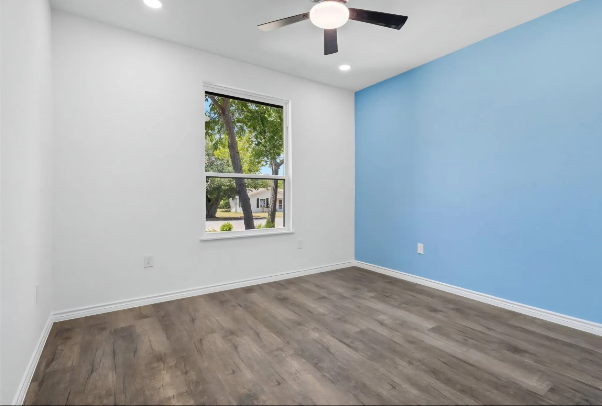 Wood-finish flooring, recessed lighting, ceiling fan with light, and a prominent accent wall