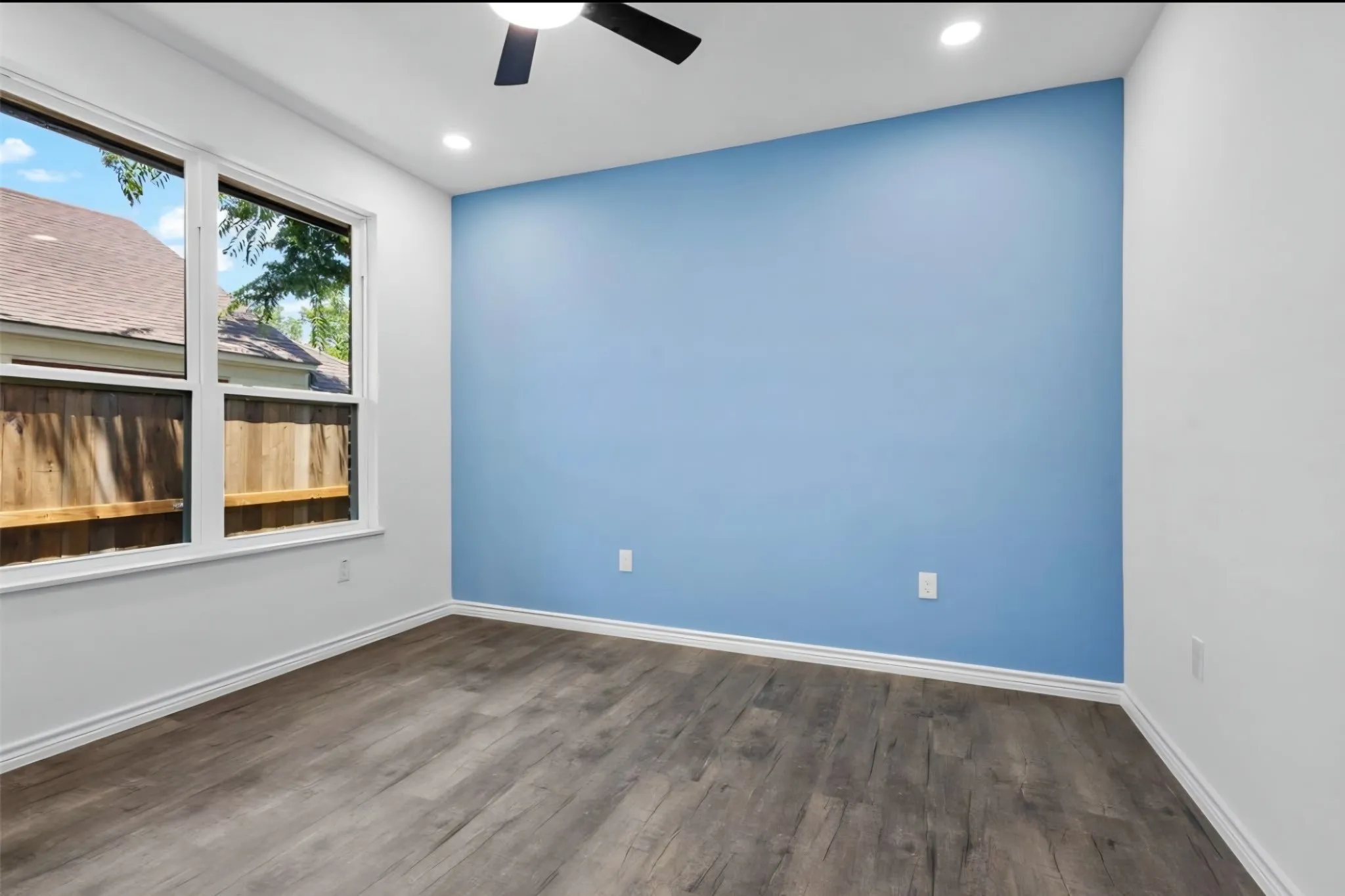 Wood-finish flooring, recessed lighting, ceiling fan, and a light-colored accent wall