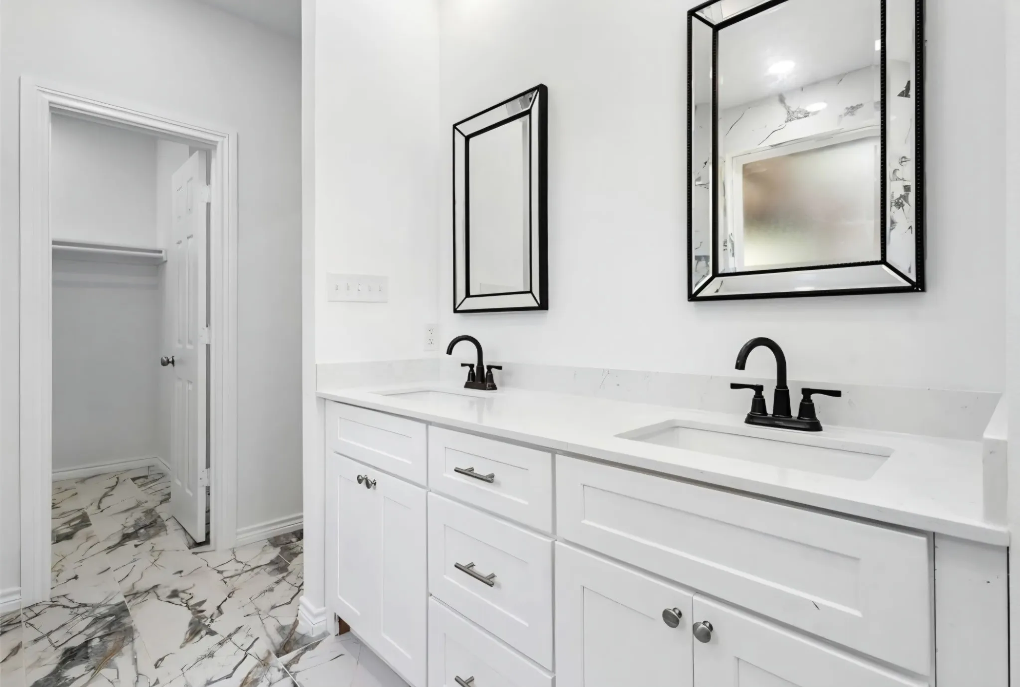 Double vanity with integrated sinks, white cabinetry, matte black fixtures, and framed mirrors