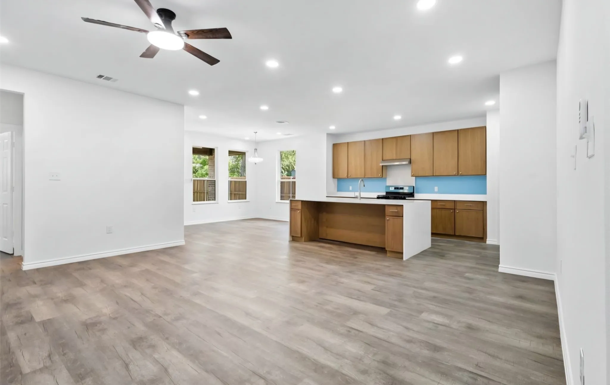 Recessed lighting, wood-finish flooring, kitchen island, wood cabinetry, and a ceiling fan