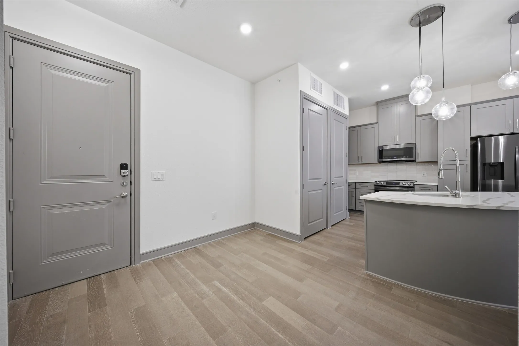 Full kitchen with a central island, pendant lighting, stainless steel appliances, and wood-finish flooring