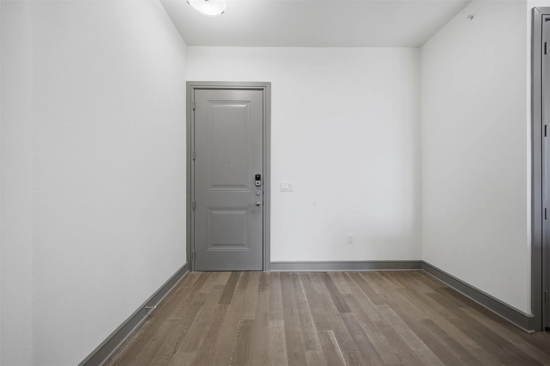 Wood-finish flooring with coordinating base trim and a panel door