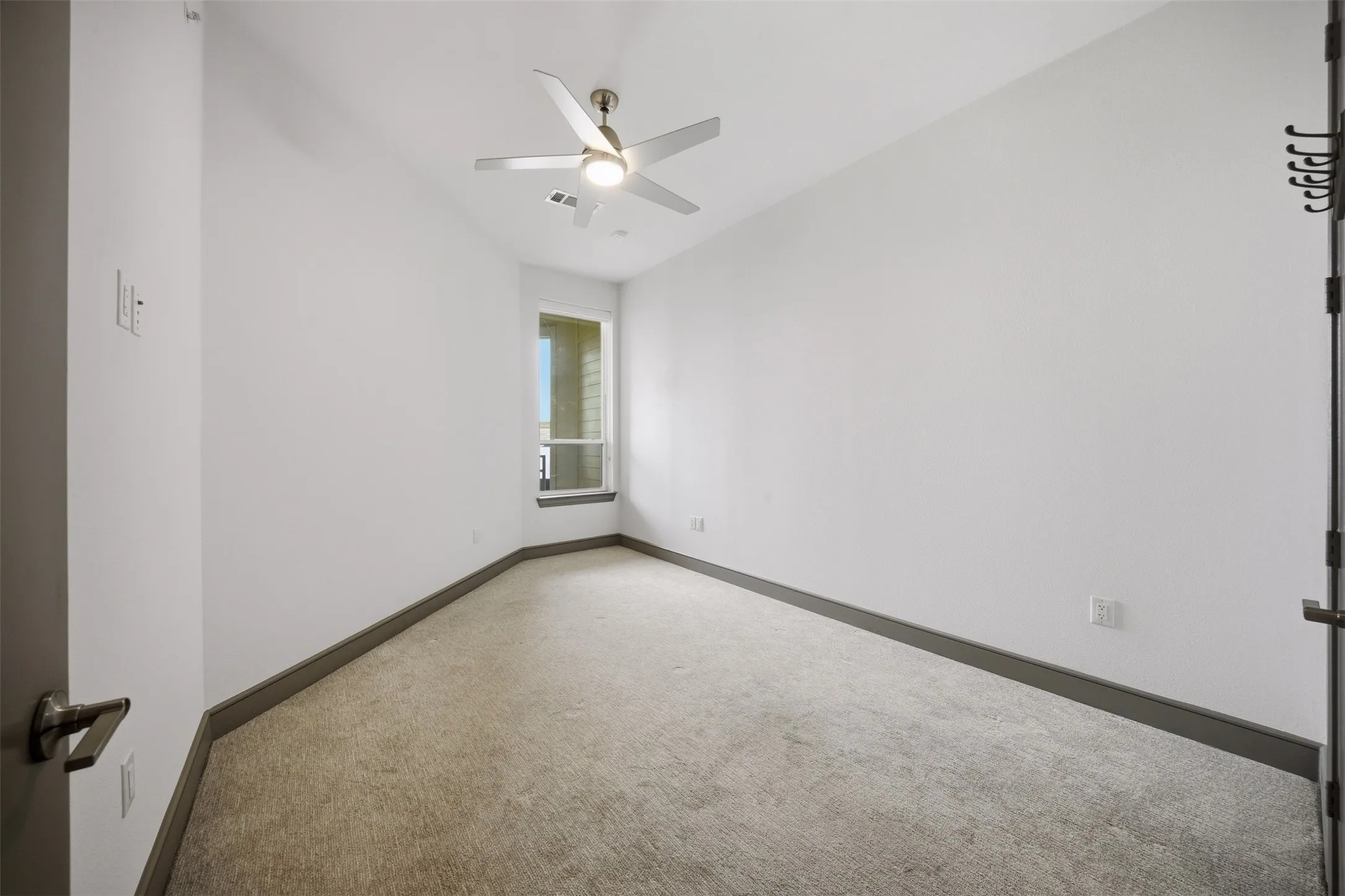 Recessed window with dark trim, ceiling fan with integrated lighting, and neutral carpeting