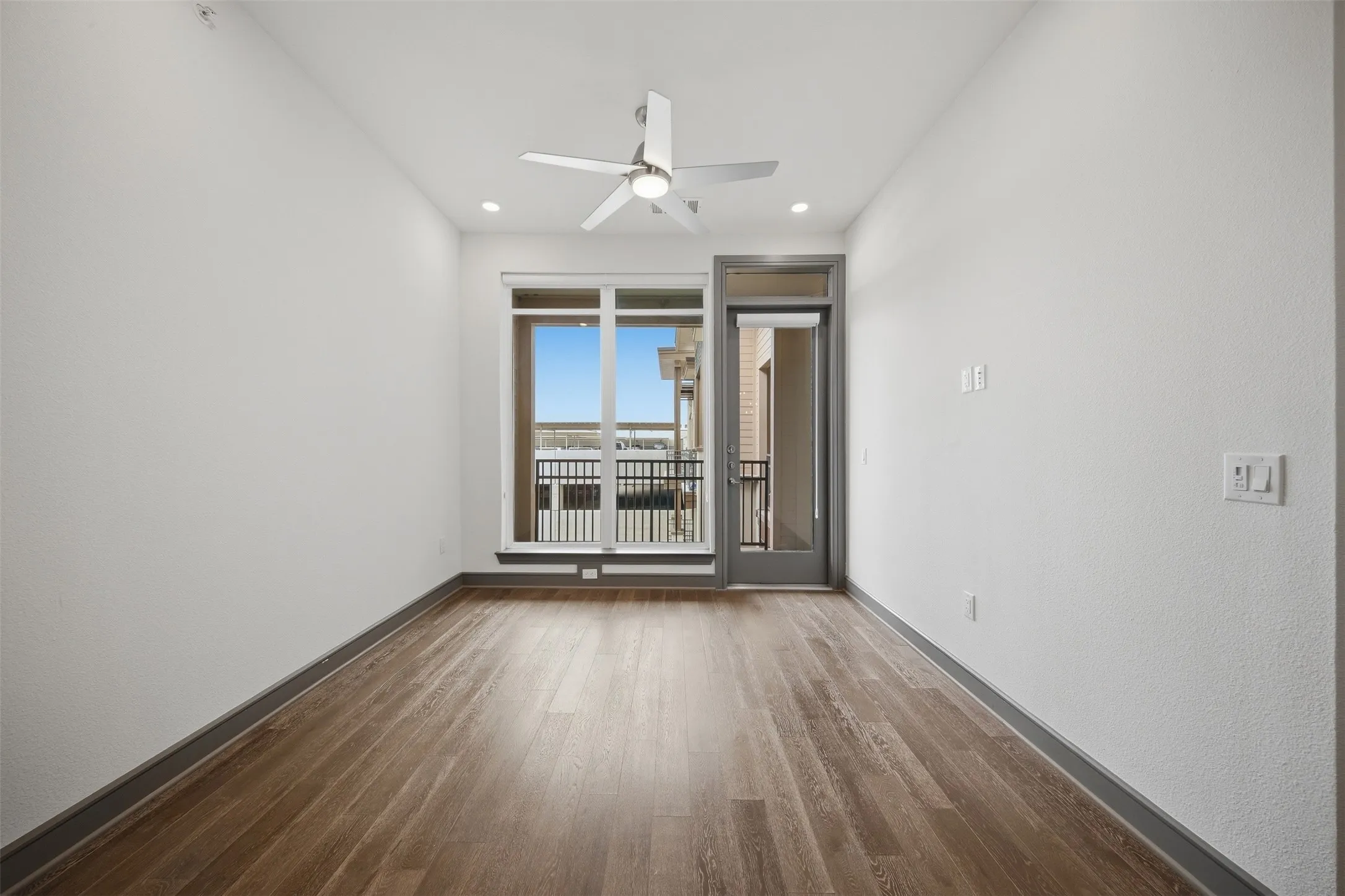 Wood-finish flooring, recessed lighting, ceiling fan, and access to an outdoor balcony