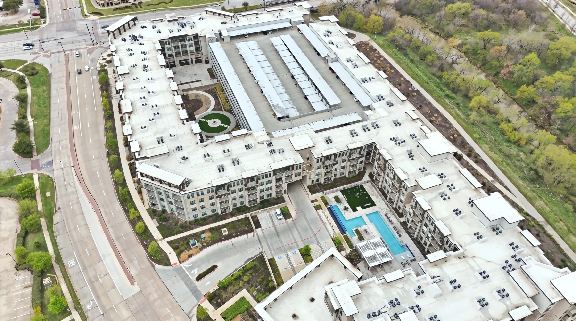 Multi-story building featuring multiple balconies, a central courtyard, and an outdoor swimming pool