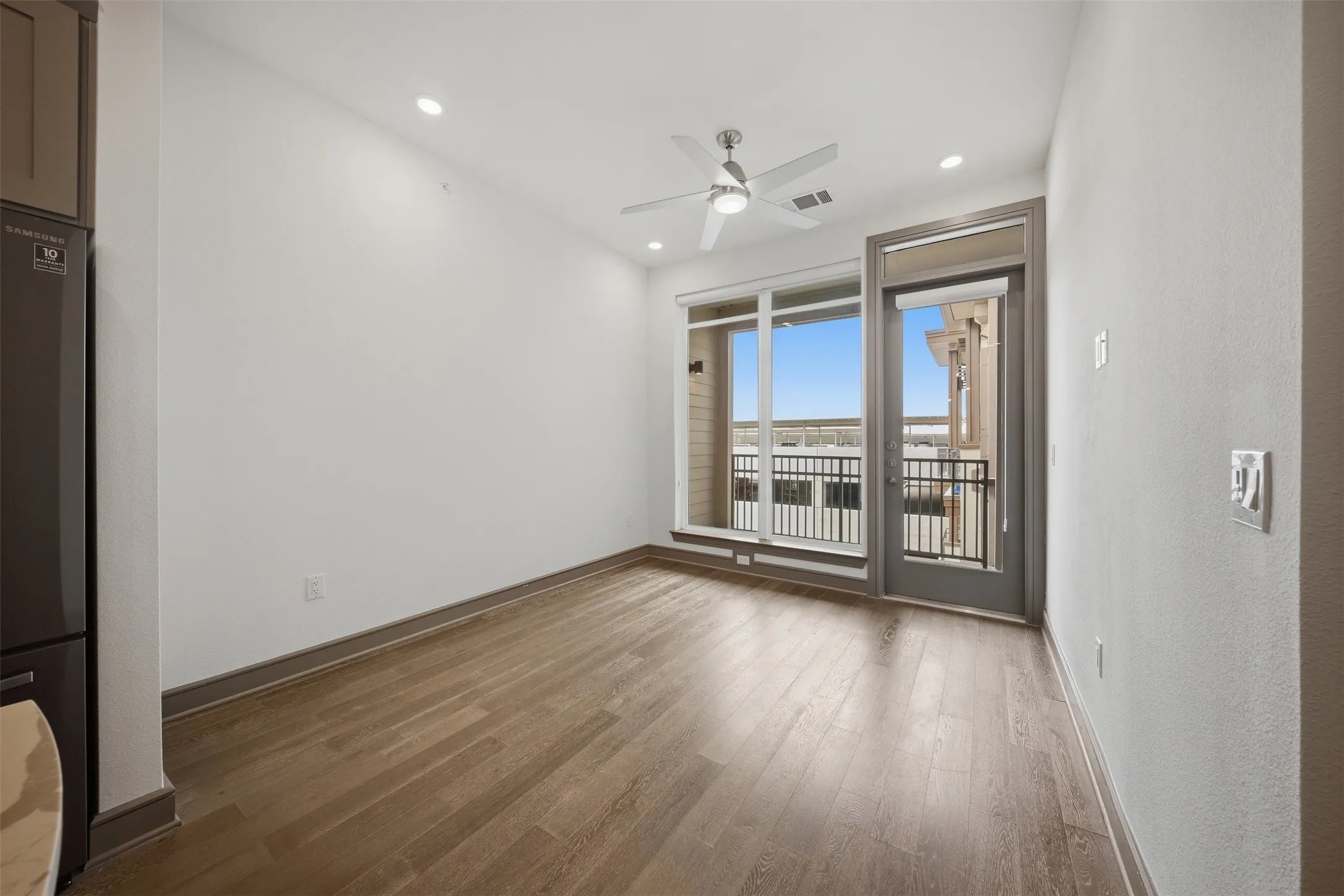 Wood-finish flooring throughout, recessed lighting, ceiling fan, and a glass-paneled exterior door