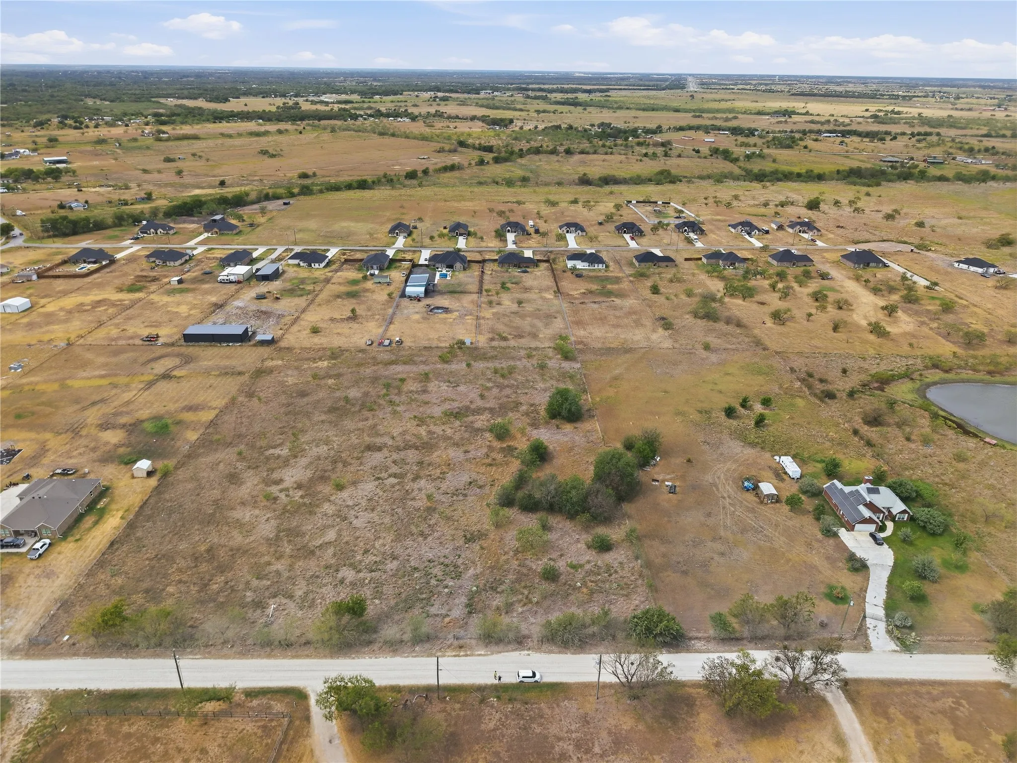 Expansive land offering a clear building site, a gravel road, and a nearby pond