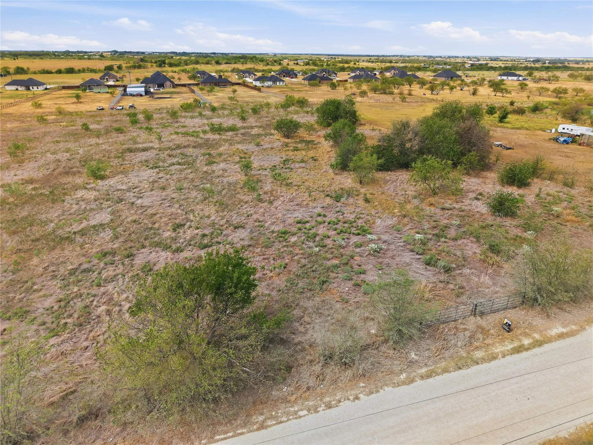 Expansive undeveloped lot with natural vegetation and distant residential properties