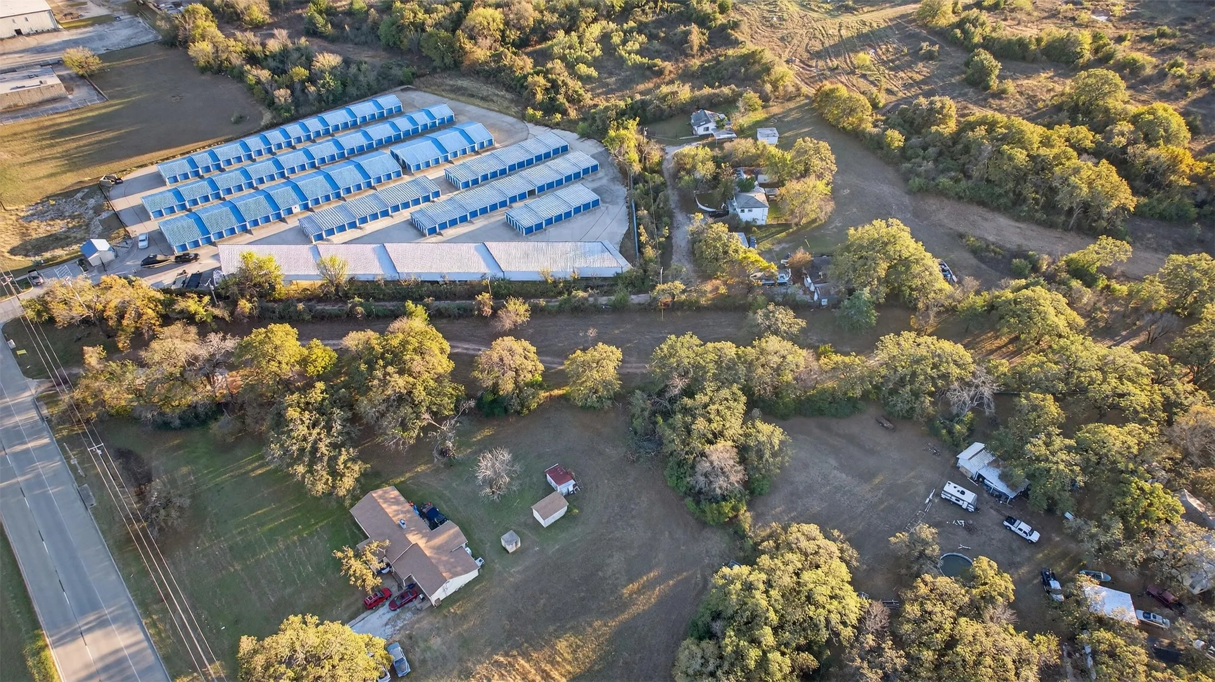 Expansive land parcel featuring multiple structures and significant tree coverage