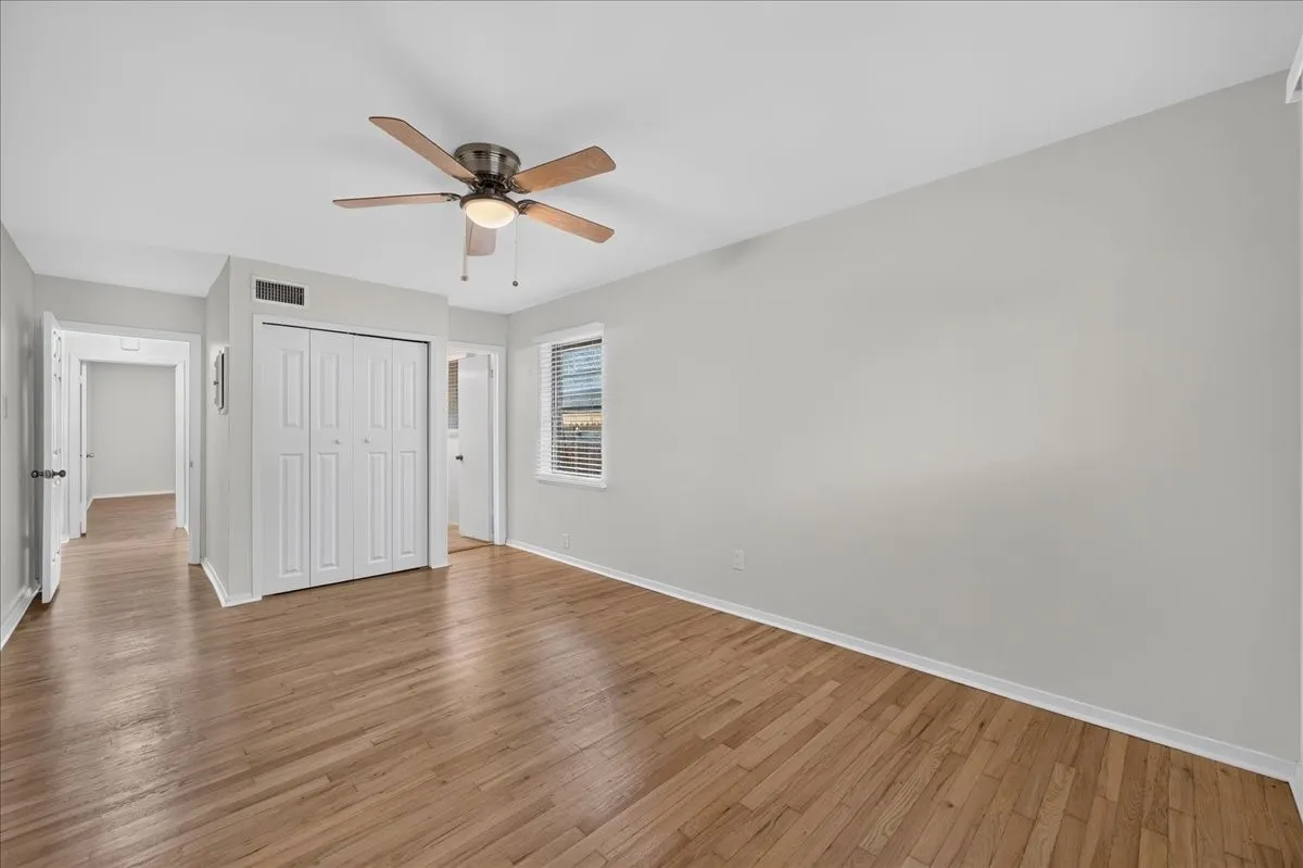 Wood-finish flooring, ceiling fan with integrated lighting, window with blinds, and bi-fold closet doors