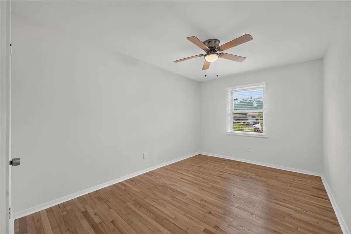 1st Bedroom features hardwood flooring complemented by a ceiling fan with integrated lighting