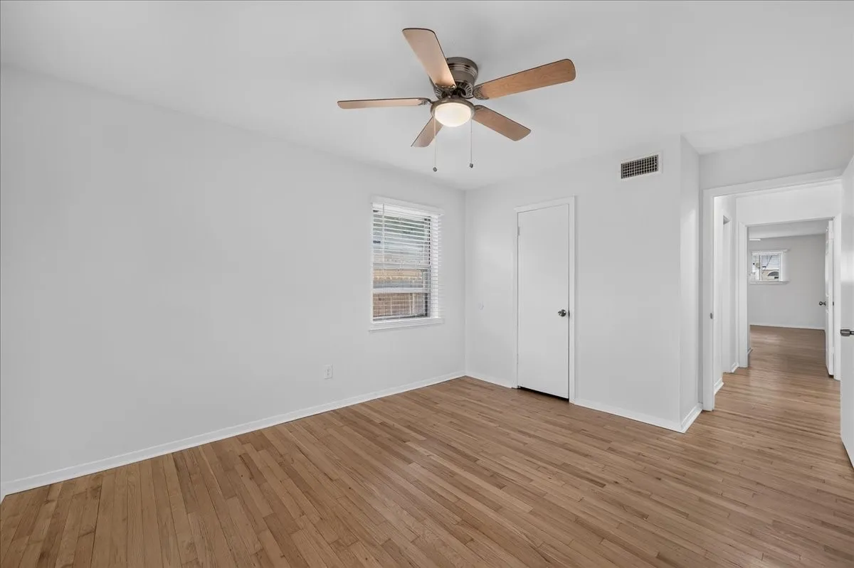 2nd bedroom has hardwood flooring throughout, white walls, and a ceiling fan with integrated lighting