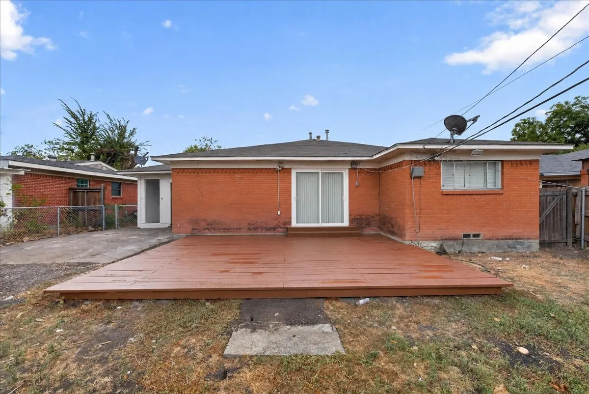 Brick exterior with a ground-level deck, sliding glass door access, and a concrete driveway