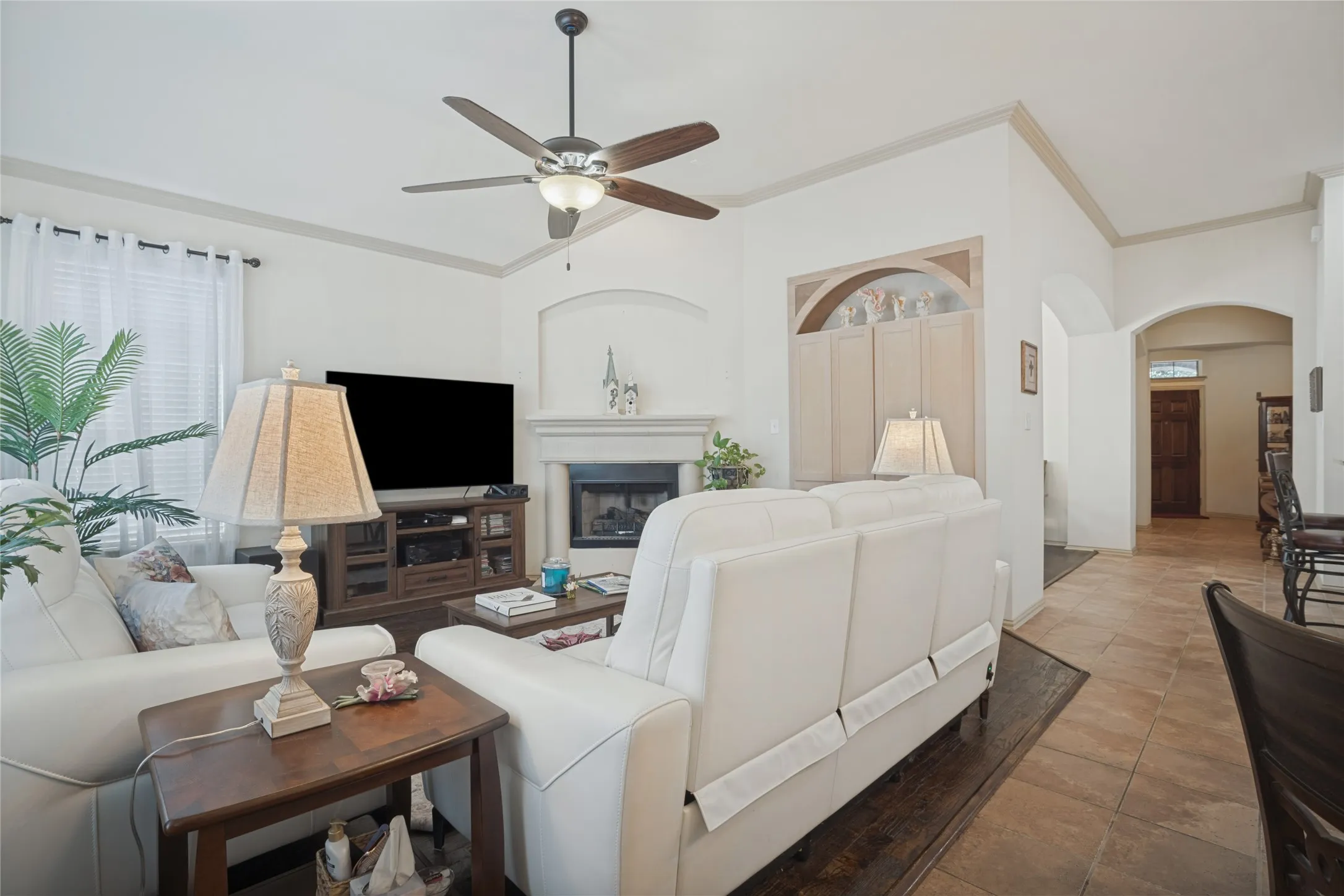 A warm and inviting living area featuring a cozy fireplace, abundant natural light, and a beautiful wall of windows overlooking the backyard.