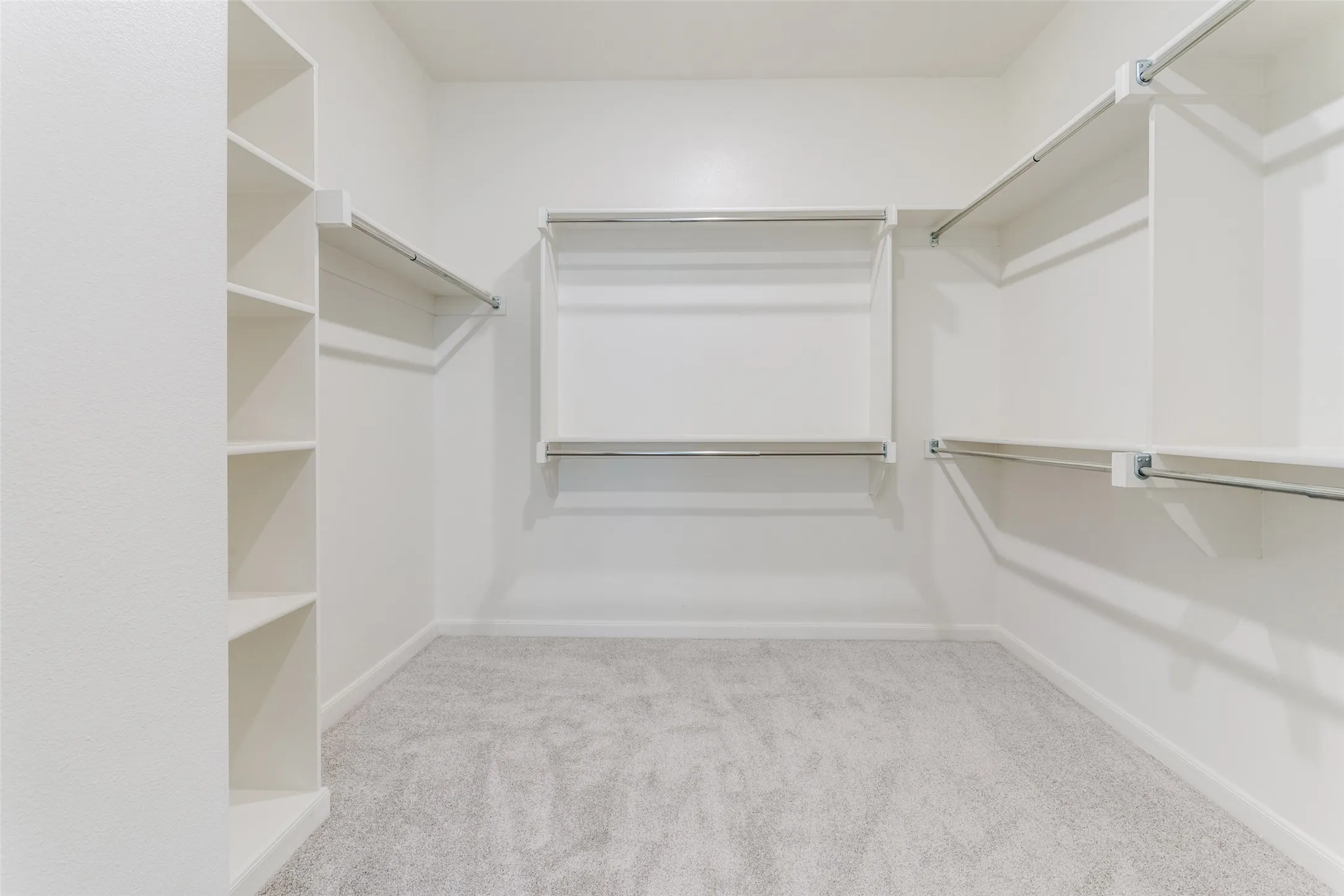 Built-in shelving, hanging rods, light-toned carpeting, and white wall finishes