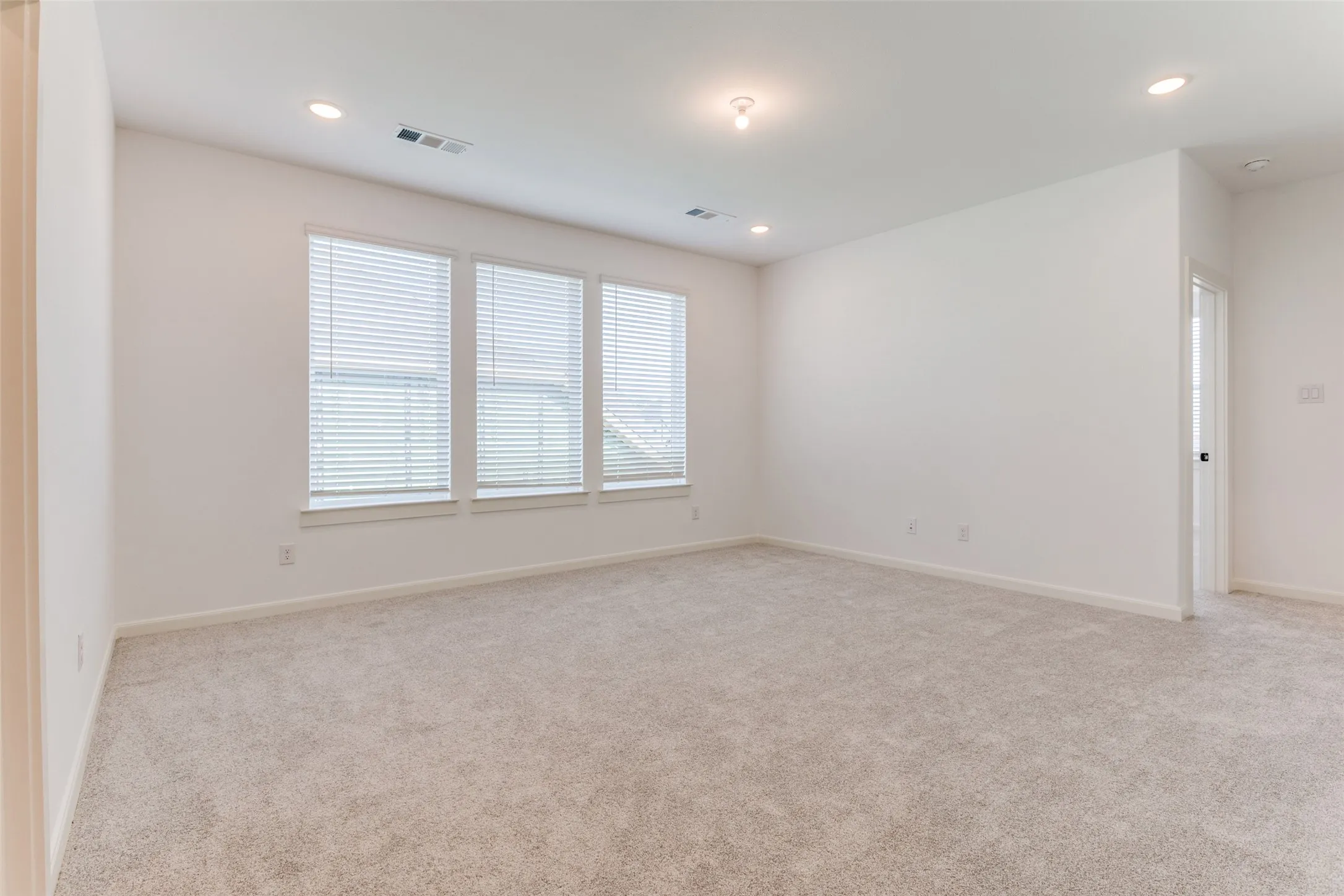 Bright interior space featuring multiple windows, recessed lighting, and neutral carpeting