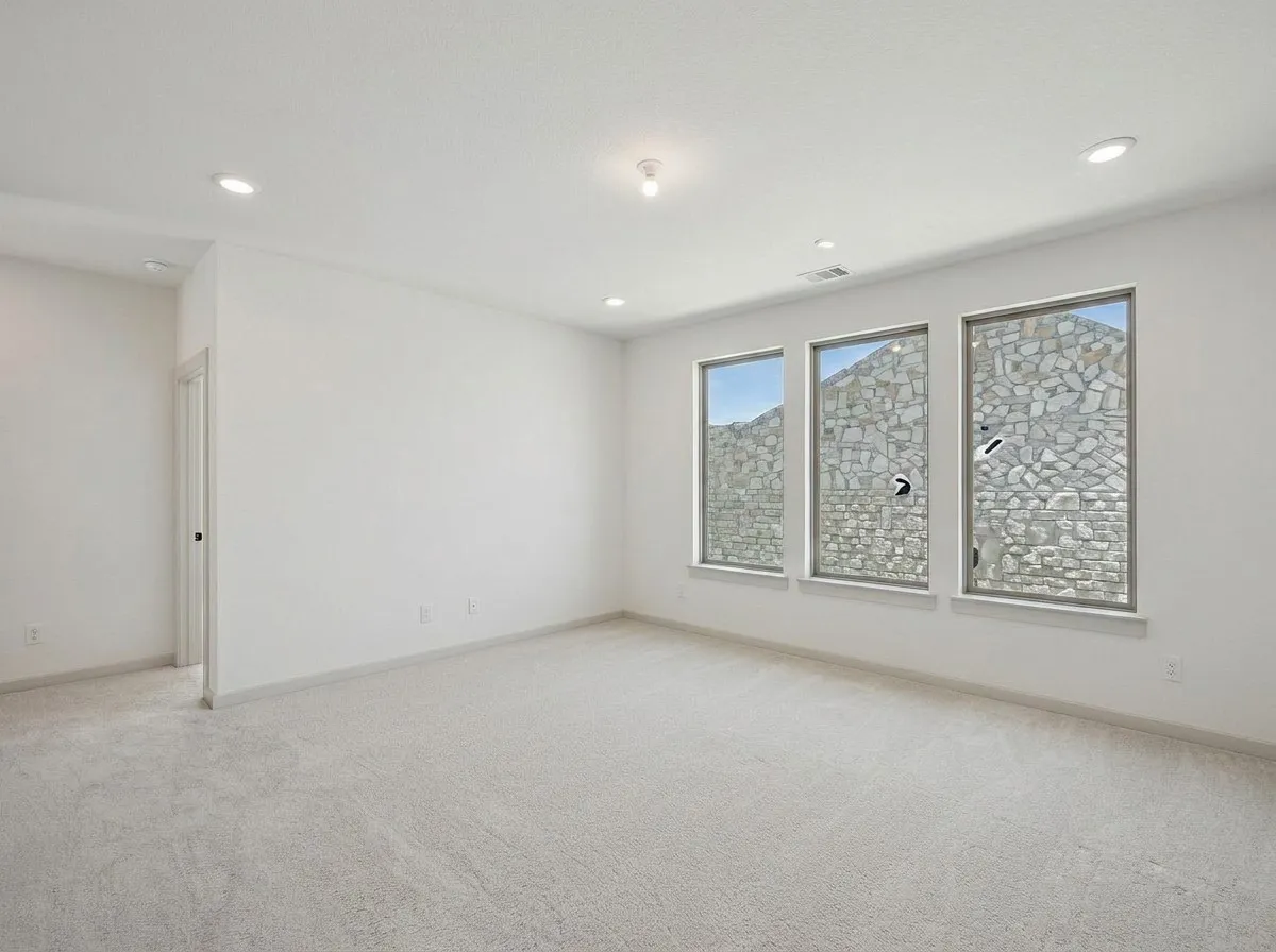 Spacious room featuring light-colored carpet flooring, recessed lighting, and three rectangular windows