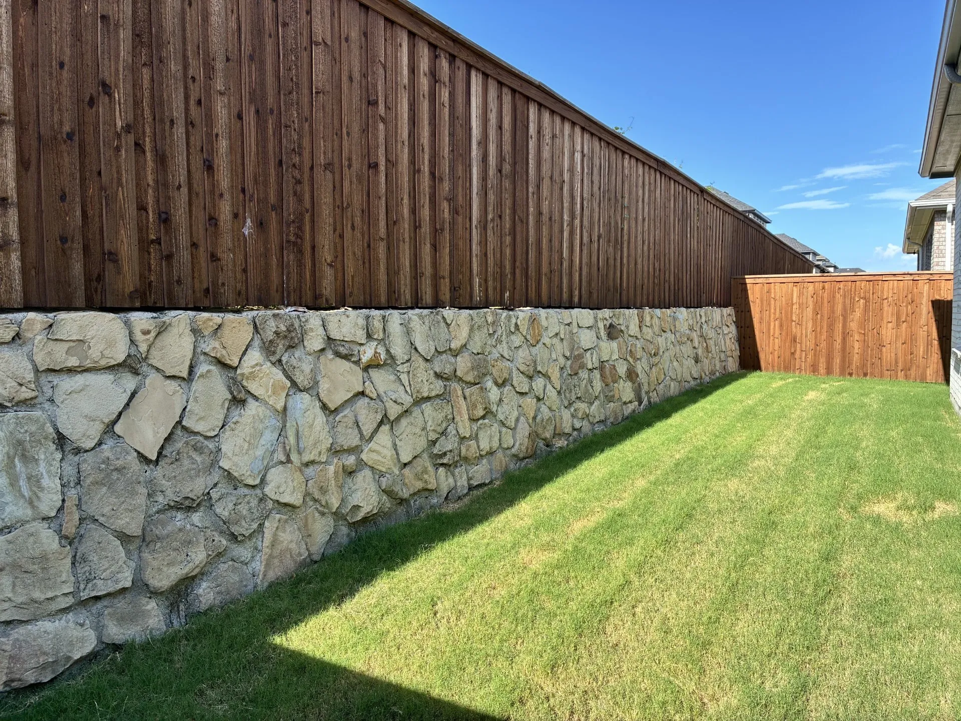 Private backyard featuring a stone retaining wall and wood fencing