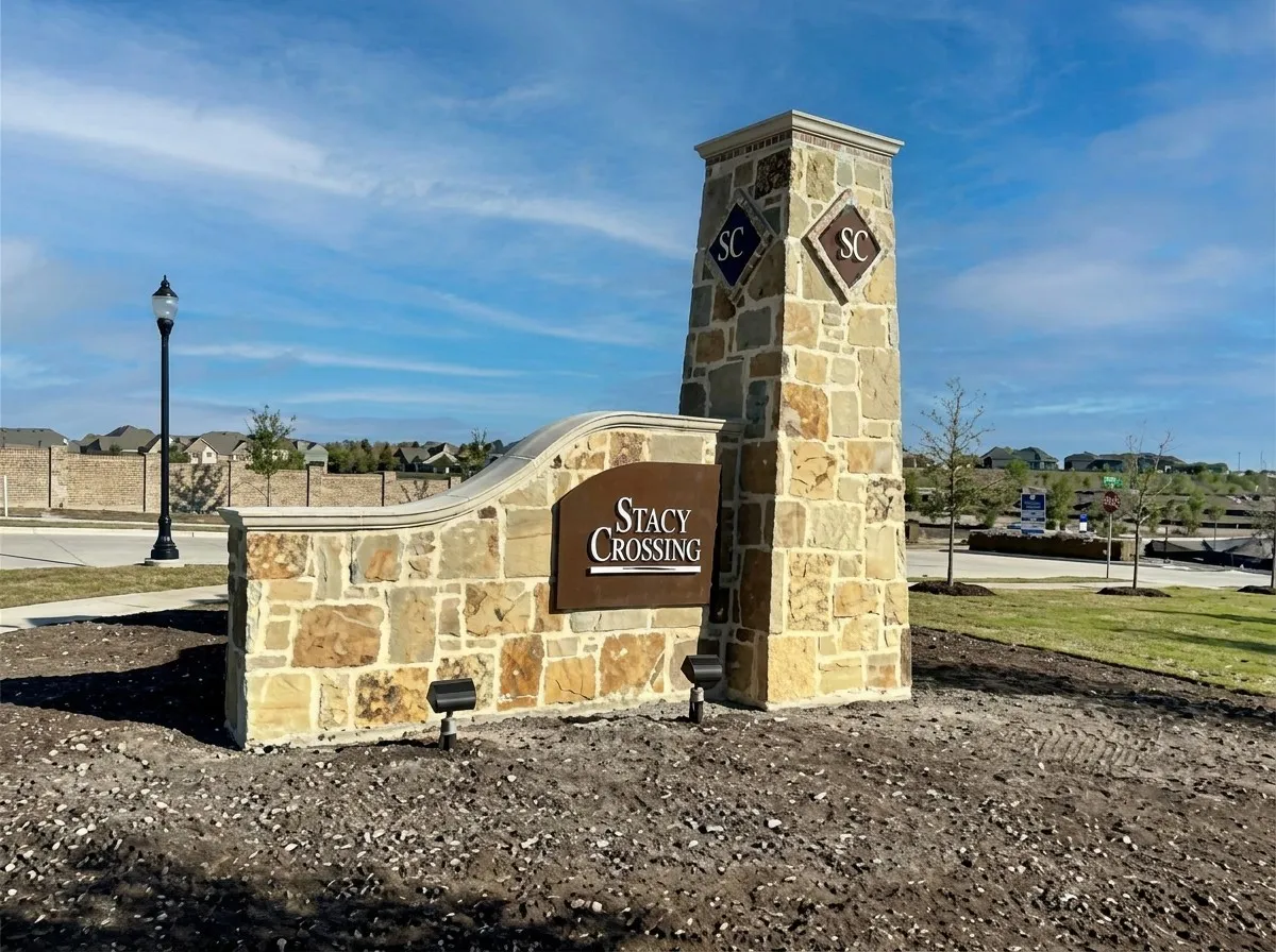 Stone-clad entry monument with integrated lighting, featuring "Stacy Crossing" signage