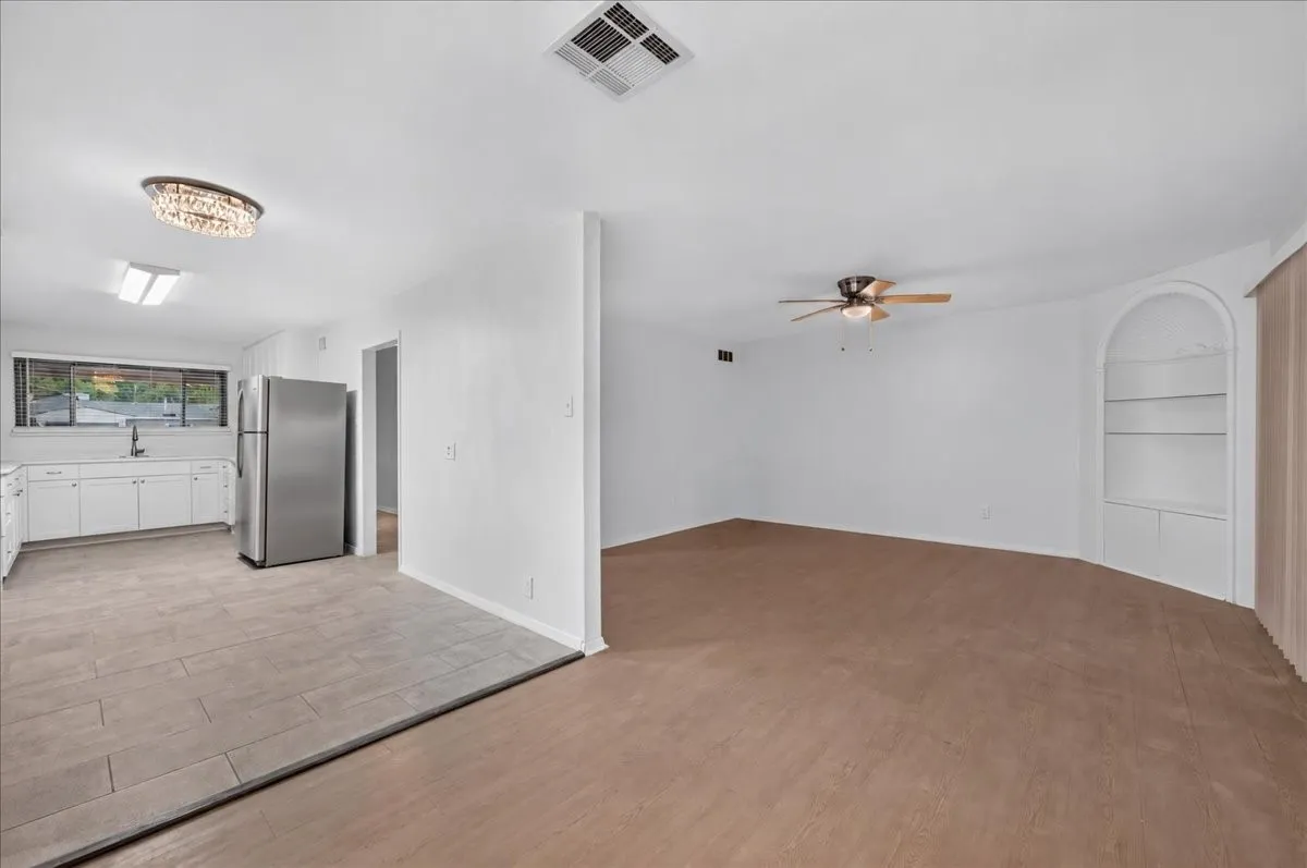 White cabinetry, stainless steel refrigerator, tile flooring, built-in shelving, and a ceiling fan