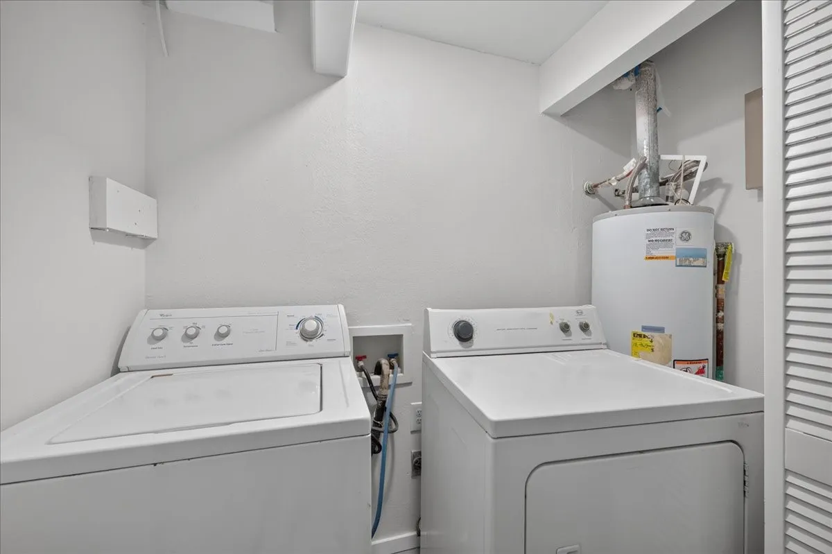 Dedicated laundry area featuring a washer, dryer, and water heater