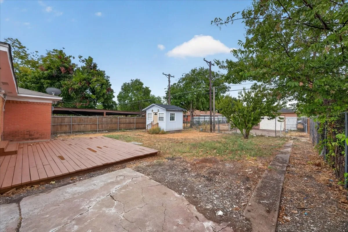 Expansive backyard featuring a wood-finish deck, concrete patio, and a standalone shed