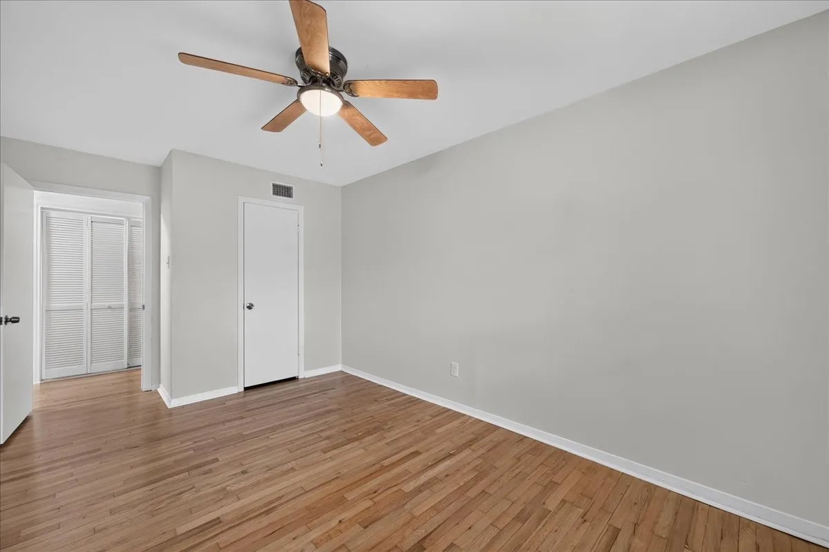 Wood-finish flooring, light gray wall paint, and a ceiling fan with light fixture